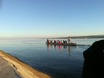 People sitting on boat in sea against sky