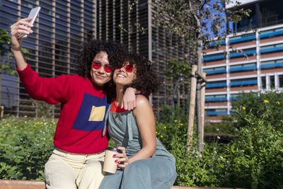 Smiling lesbian couple doing selfie while sitting outdoors