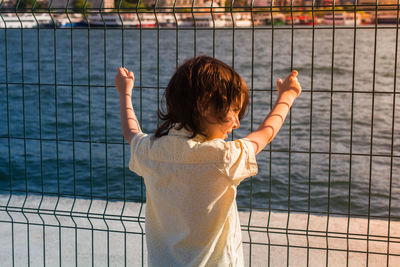 Rear view of boy standing by railing