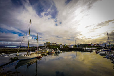 View of marina at harbor against cloudy sky