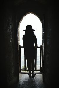 Rear view of silhouette man standing at entrance of building