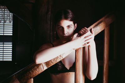 Portrait of young woman standing by railing at home