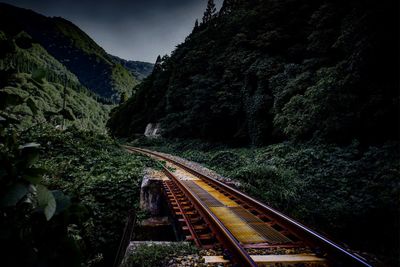 Railroad tracks by mountain against sky