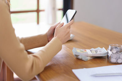 Midsection of woman using digital tablet on table