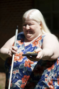 Smiling woman holding gift box standing outdoors