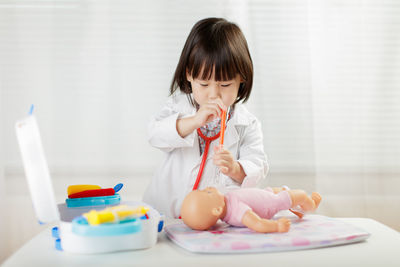 Cute doctor playing with toys on table