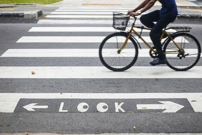 High angle view of road sign against man riding bicycle on zebra crossing