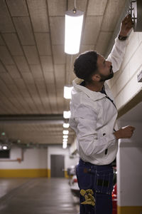 Rear view of man checking air duct