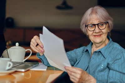 Portrait of senior woman with document sitting at table