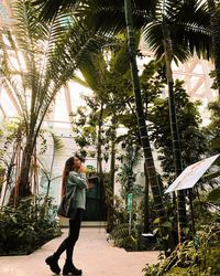 Side view of woman standing on palm trees