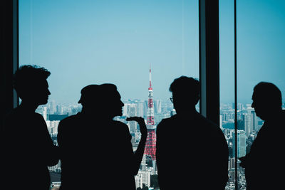 Rear view of silhouette business person having discussion while standing by window at office