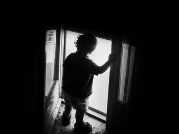 Rear view of man standing against door at home