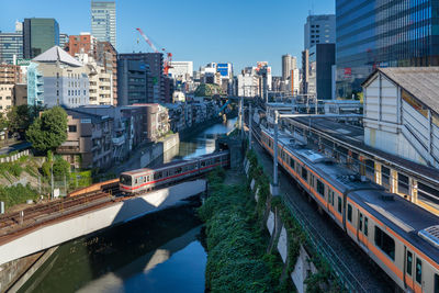 High angle view of train on bridge over canal amidst buildings in city