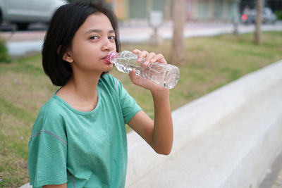 Portrait of teenage girl drinking water outdoors