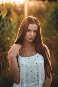 Portrait of young woman standing against plants