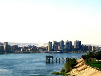 River by buildings against clear sky