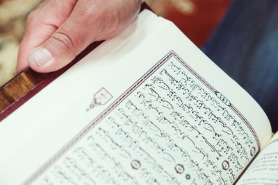 Cropped hands of man reading koran in mosque