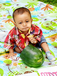 Portrait of cute boy sitting with fruit