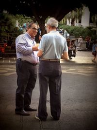 Rear view of men with man standing outdoors