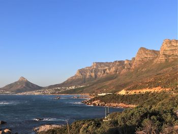 Scenic view of sea and mountains against clear blue sky