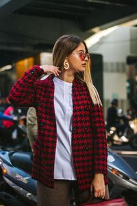 Young woman standing on road against motorcycles