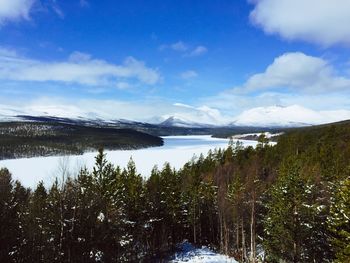 Scenic view of lake by snowcapped mountains against sky