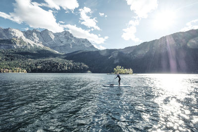 Germany, bavaria, garmisch partenkirchen, young woman stand up paddling on lake eibsee