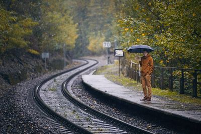 Rear view of man walking on railroad track