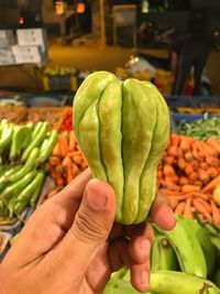 Cropped image of hand holding fruits at market stall