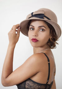 Portrait of young woman wearing hat against white background