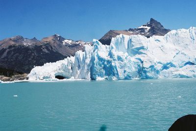 Scenic view of sea and snowcapped mountains against clear sky