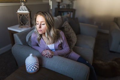 Full length of woman sitting on sofa at home