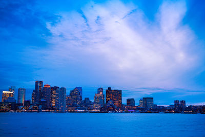 Sea by buildings against blue sky