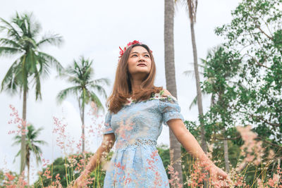 Low angle view of woman standing against trees