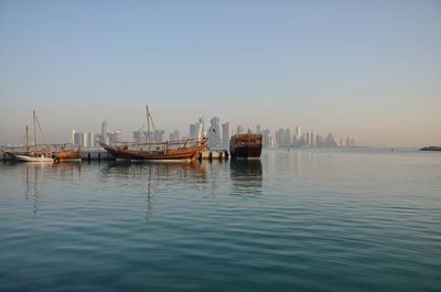 Sailboats moored in sea against clear sky