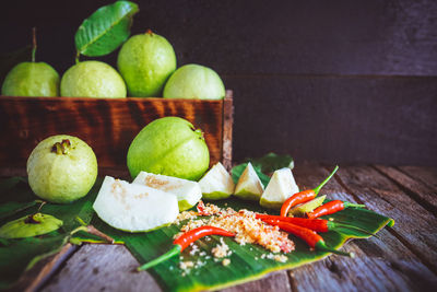 Close-up of guavas with red chili pepper on floorboard