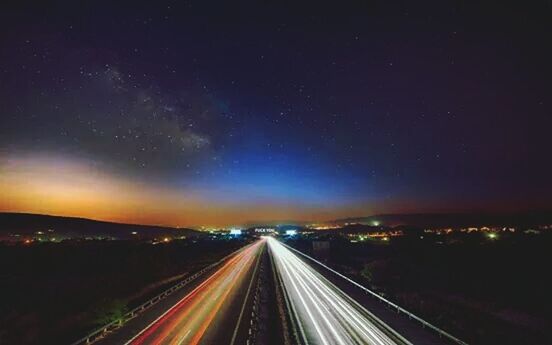illuminated, night, transportation, road, the way forward, long exposure, light trail, diminishing perspective, vanishing point, highway, sky, motion, road marking, speed, blurred motion, landscape, high angle view, no people, scenics, outdoors