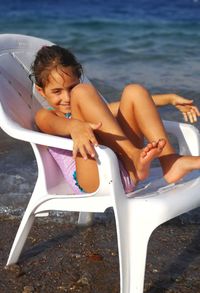 Boy sitting on beach against sky