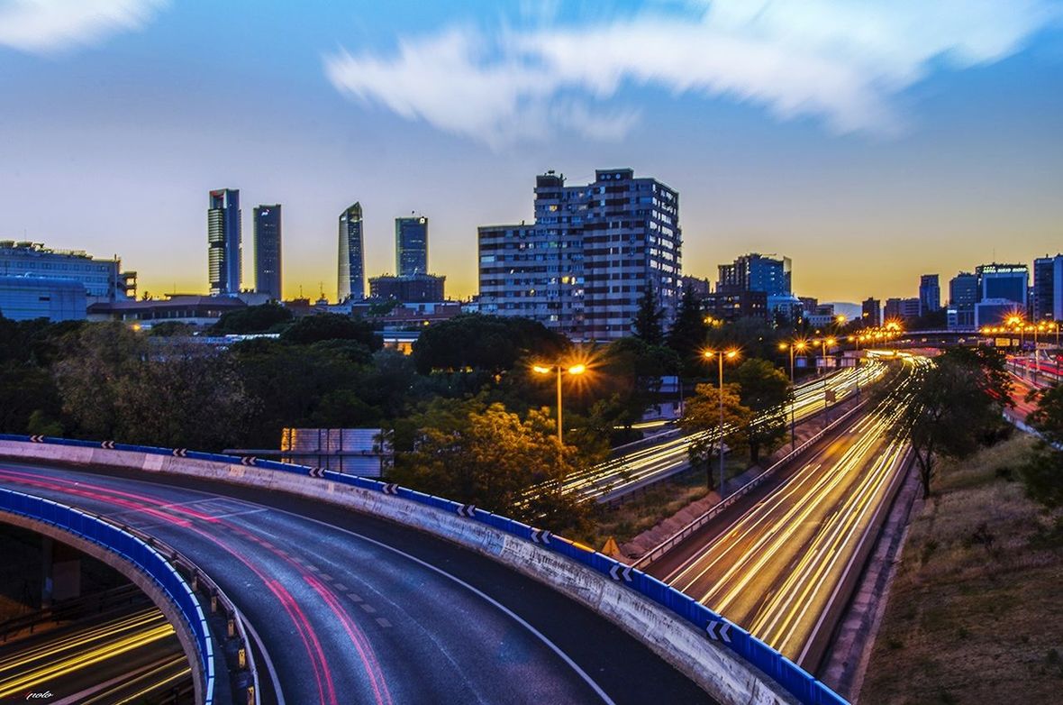 HIGH ANGLE VIEW OF LIGHT TRAILS ON ROAD AGAINST SKY