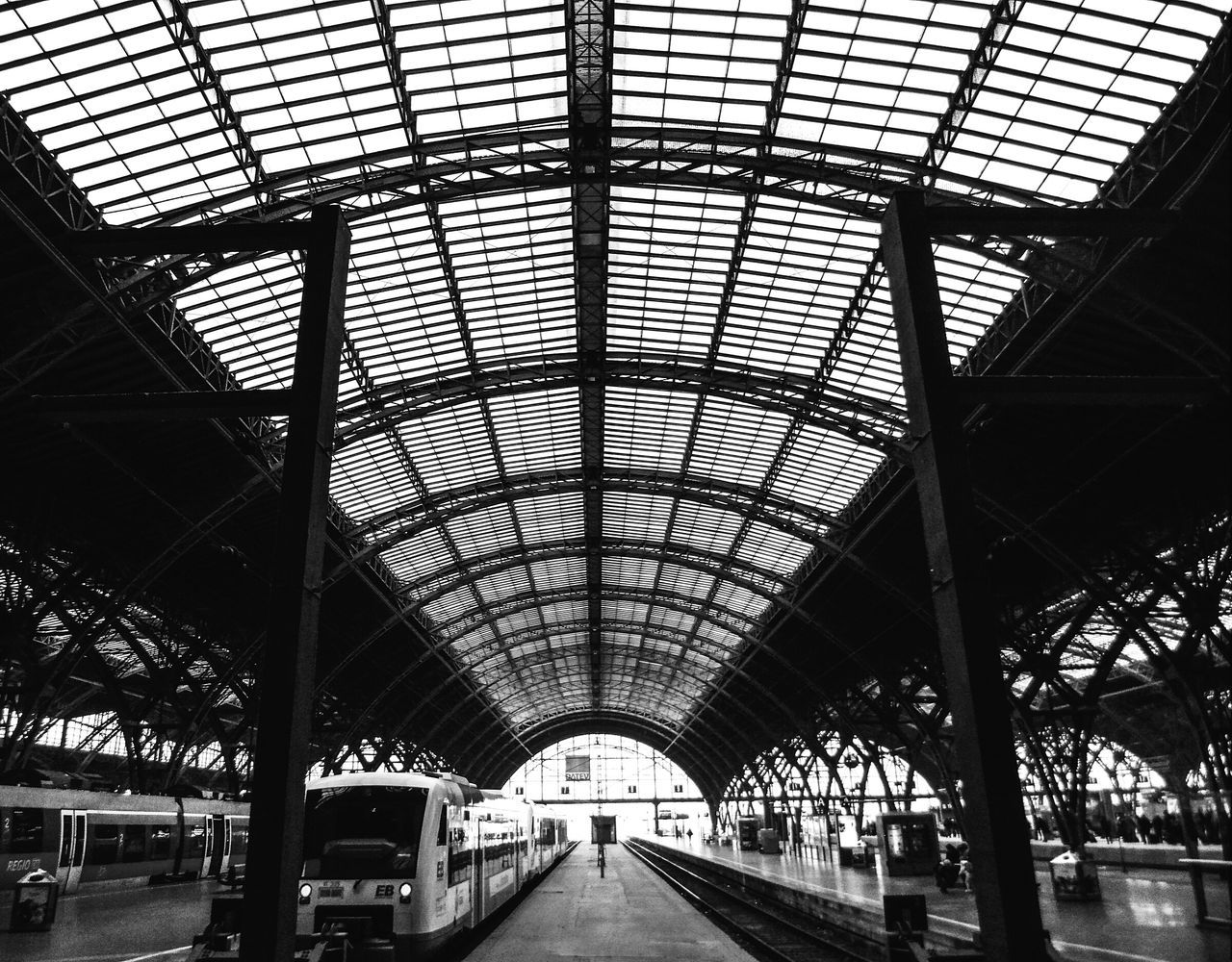 indoors, ceiling, architecture, transportation, built structure, railroad station, public transportation, rail transportation, the way forward, railroad station platform, diminishing perspective, interior, incidental people, transportation building - type of building, railroad track, travel, vanishing point, empty, illuminated, arch