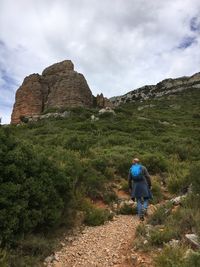 Rear view of man walking on mountain against sky