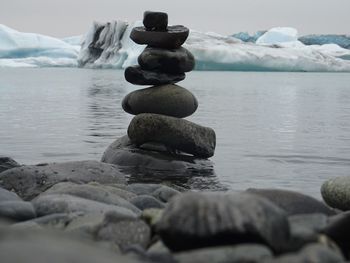 Stack of pebbles on beach against sky