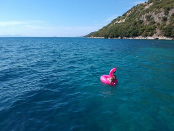 Woman swimming with pink inflatable ring in sea during sunny day