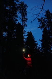 Rear view of woman standing against trees