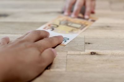 Cropped hand of person holding paper currency on table