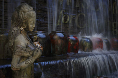 Statue against blurred flowing water