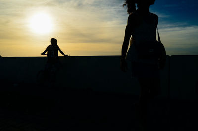 Silhouette people standing on beach against sky during sunset