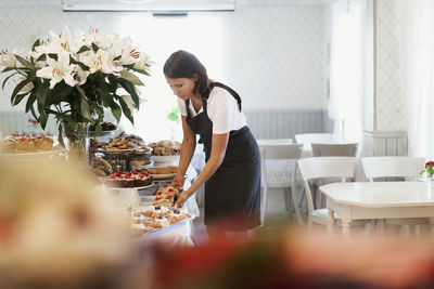 Woman standing by flowers on table