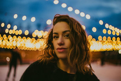 Portrait of woman looking at illuminated lamp