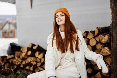 Portrait of smiling young woman sitting against logs